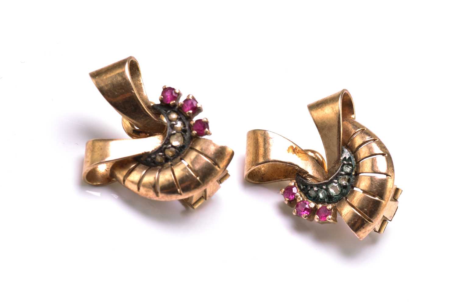 A pair of ribbon motif earrings, each set with diamond and ruby accents, backed with peg and clip