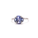 A 9ct white gold, diamond, and tanzanite flower head ring set with four trillion-cut tanzanites