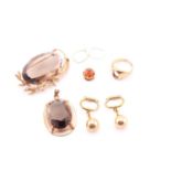 A smoky quartz brooch, the large faceted oval stone in a textured scrolling, foliate mount,