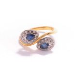 A sapphire and diamond ring, consisting of two pear-shaped sapphires claw-set on white metal mounts,