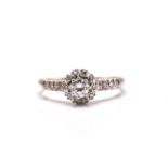 A diamond entourage ring in white precious metal, starring a brilliant diamond claw set in the