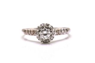 A diamond entourage ring in white precious metal, starring a brilliant diamond claw set in the
