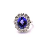 A platinum tanzanite entourage ring, featuring an oval mixed-cut tanzanite with intense purplish-