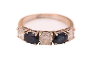 A sapphire and diamond ring, consisting of two oval sapphires alternating with three round brilliant