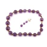 An amethyst bead necklace and a similar single earring; the necklace has twenty-one amethyst round