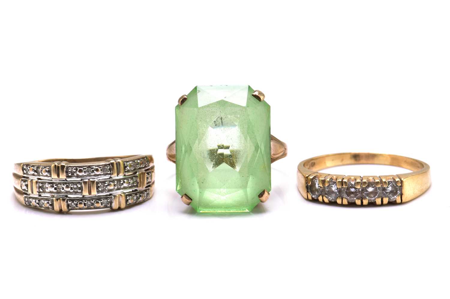 A lot with three gem-set rings, to include a green paste ring, comprises a scissors cut green past
