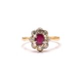 An 18ct gold and platinum diamond and ruby cluster ring, comprises an oval ruby in the centre,