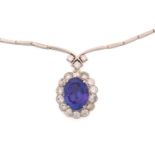 A tanzanite and diamond halo necklace, featuring an oval fancy cut tanzanite with intense purplish