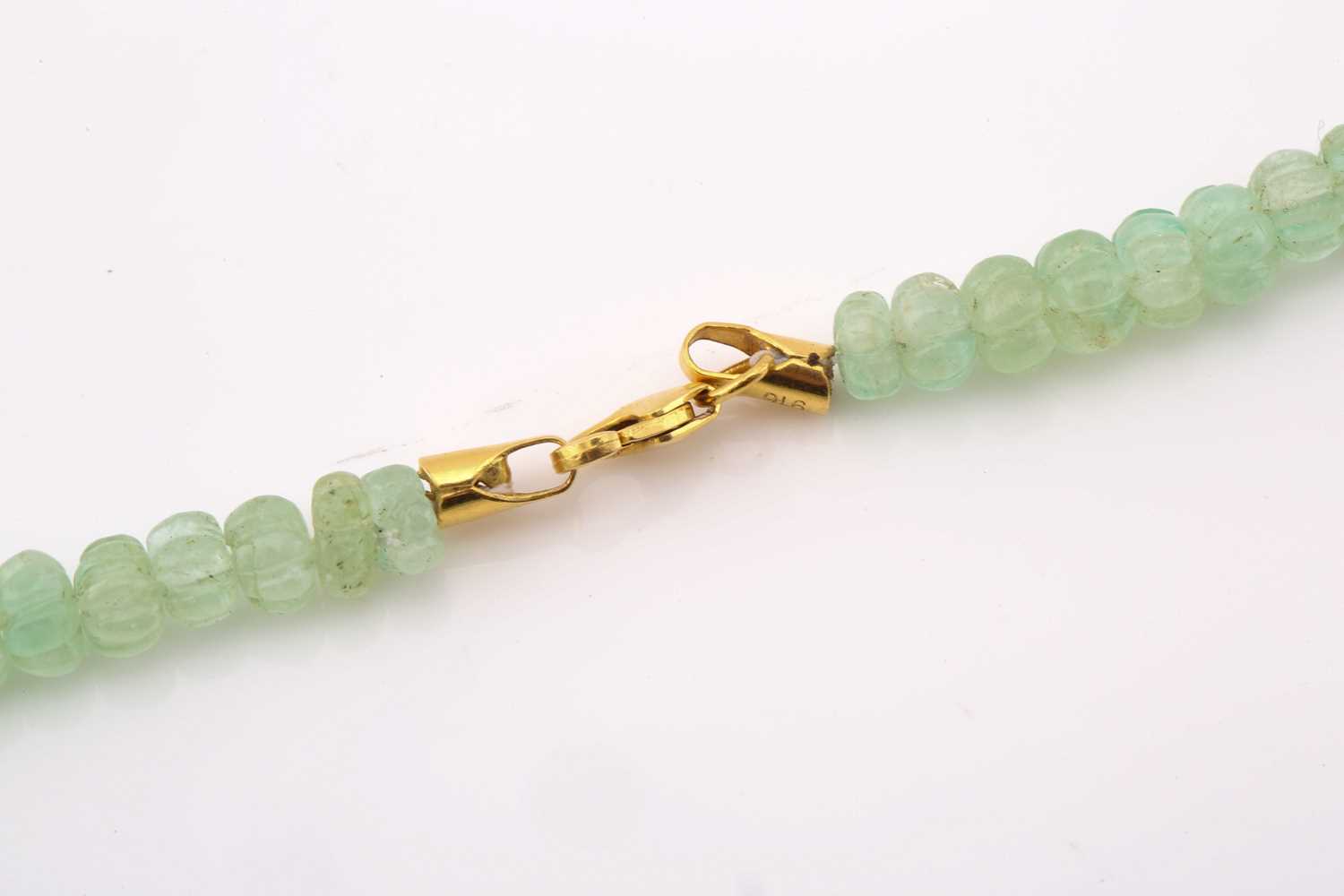 A carved emerald bead necklace, comprising a string of ninety-one reeded emerald beads in pale green - Image 2 of 5