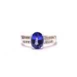 An 18ct white gold tanzanite and diamond dress ring, featuring an oval fancy cut tanzanite with an