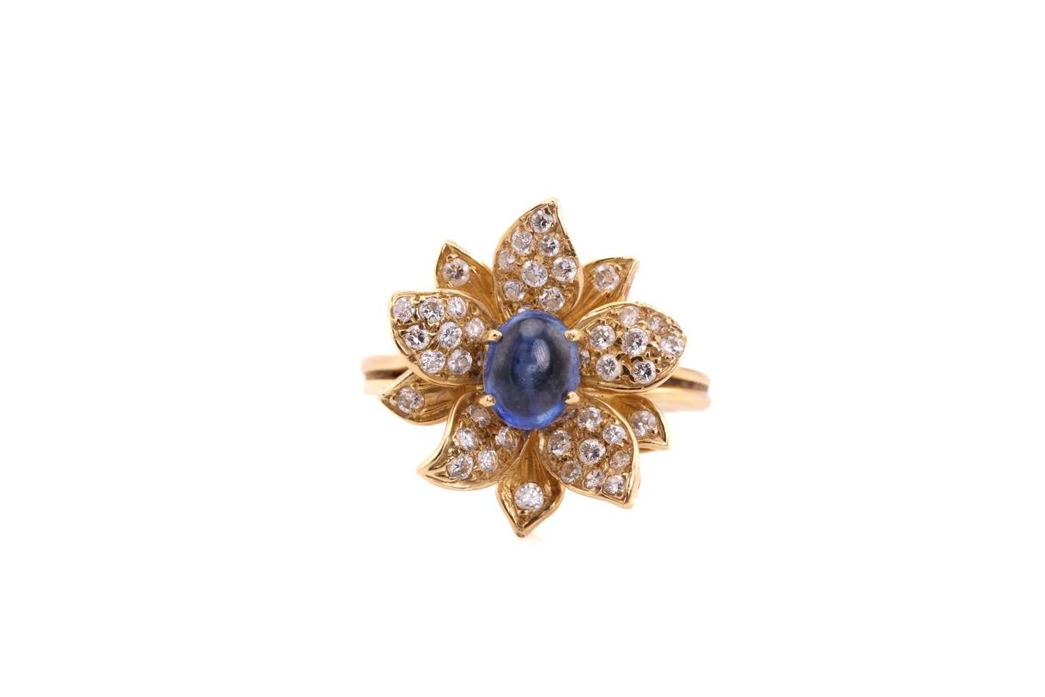 An 18ct gold sapphire and diamond flower ring, comprises an oval sapphire cabochon with a high dome,