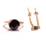 A sapphire ring and a matching necklace, the ring has a cushion-cut opaque sapphire in dark blue