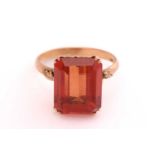 A synthetic orange sapphire ring, with an emerald-cut synthetic sapphire in reddish-orange colour,