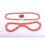 A lot consisting of a coral necklace, a coral coloured necklace and one coral brooch, the first