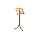 An Edwardian golden oak adjustable music stand with fluted column on an outswept tripod base with