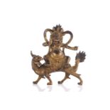 A Chinese gilt bronze figure of Jambhala, a serpent in his fist entwined around his fight arm,