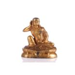 A Chinese Sino Tibetan style gilt bronze figure of Milarepa, his right hand cupped to his ear, a