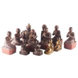 A set of six carved wood Tibetan praying monks, each with traces of gilding on a black lacquer
