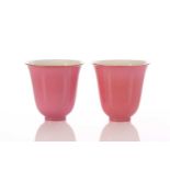 A pair of Chinese peach bloom bell shape cups, the flared rim with gilt decoration, the body a