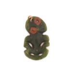 A New Zealand Maori Tiki greenstone pendant, with red wax eyes and tilting head, 5.9 cm x 3.4 cm