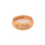 A three-stone diamond gypsy ring in 18ct gold, comprises three old-cut diamonds star set on a yellow