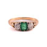 An emerald and diamond three-stone ring, comprises a cushion step-cut emerald in the centre