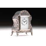 An Edwardian boudoir clock; white enamel rectangular dial with Roman numerals; set within an