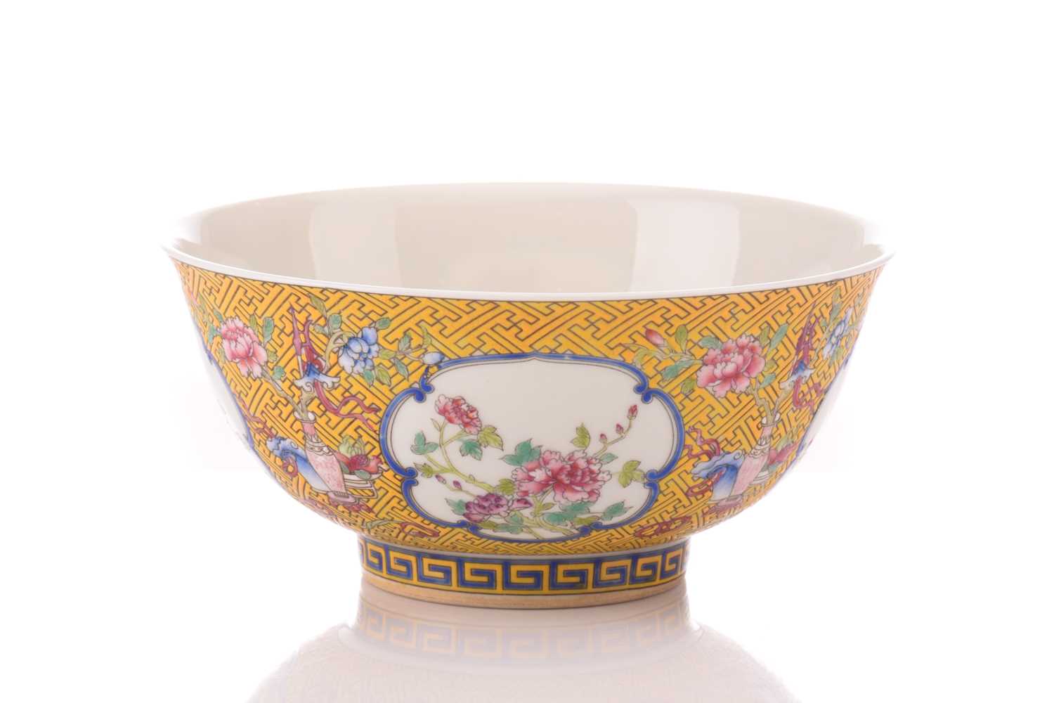 A Chinese porcelain bowl, painted with medallions of auspicious flowers and flanked by treasures,