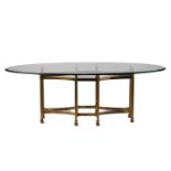 A large 20th-century 'Hollywood Regency' oval plate glass dining table with a heavy gilt brass