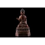 A Chinese bronze figure of Buddha, seated in Abhaya mudra, the hair in tight curls, seated on a