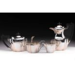 A George V silver four-piece silver tea set, of shaped boat form with ebony finials and handles,