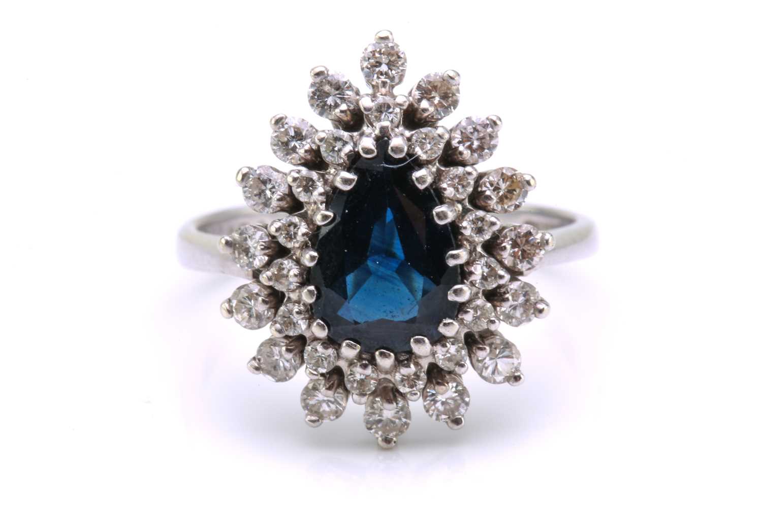 A sapphire and diamond entourage ring, featuring a pear-shaped sapphire in dark blue colour,