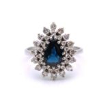 A sapphire and diamond entourage ring, featuring a pear-shaped sapphire in dark blue colour,