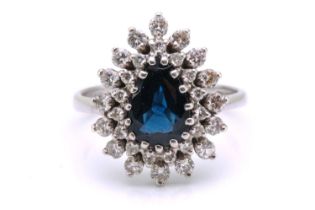 A sapphire and diamond entourage ring, featuring a pear-shaped sapphire in dark blue colour,