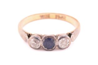 A three-stone ring with sapphire and diamonds, comprises an oval-cut sapphire in deep blue colour,