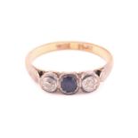 A three-stone ring with sapphire and diamonds, comprises an oval-cut sapphire in deep blue colour,