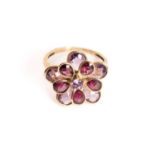 A garnet and amethyst flowerhead ring in 9ct gold, comprises two layers of openwork collets in the