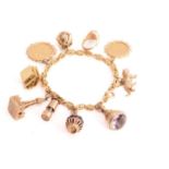 A rope chain bracelet with assorted charms, attached with mostly 9ct yellow gold charms, to