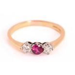 A ruby and diamond three-stone ring in 18ct gold, centred with a faceted round synthetic ruby,