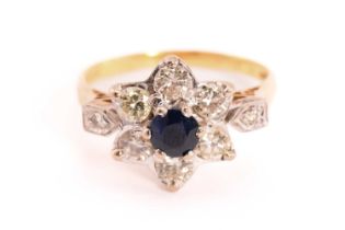 A sapphire and diamond flower head ring in 18ct gold, composed of a central faceted sapphire