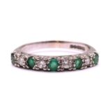 An Emerald and diamond half eternity ring in 18ct gold, with five round faceted emeralds alternating