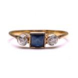 A sapphire and diamond ring, featuring a French cut sapphire collet set in the centre, flanked by