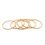 A suite of six meander bangles, with a diamond stud pattern texture on the exterior, yellow metal