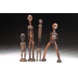 A group of four Tanzanian standing figures, one figure with articulated arms and with strings of red