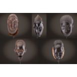 Four Baule masks and a headress mask, Ivory Coast, three with linear carved coiffures, the headdress