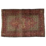 An early 20th-century claret and pistachio green ground Kerman rug with a central medallion and