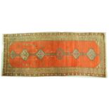 An antique tomato red ground North Western Persian long rug with six lozenges on a central pole