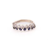 A two-row sapphire and diamond ring in 18ct white gold, comprises seven round sapphires and round