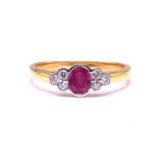 A ruby and diamond ring in 18ct gold, presenting an oval faceted ruby in the centre, flanked by