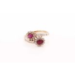 A ruby and diamond bypass ring, composed of two clusters of oval faceted rubies surrounded by